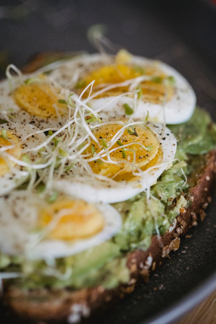Close-up of an avocado toast topped with hard-boiled eggs and sprouts, perfect for breakfast.